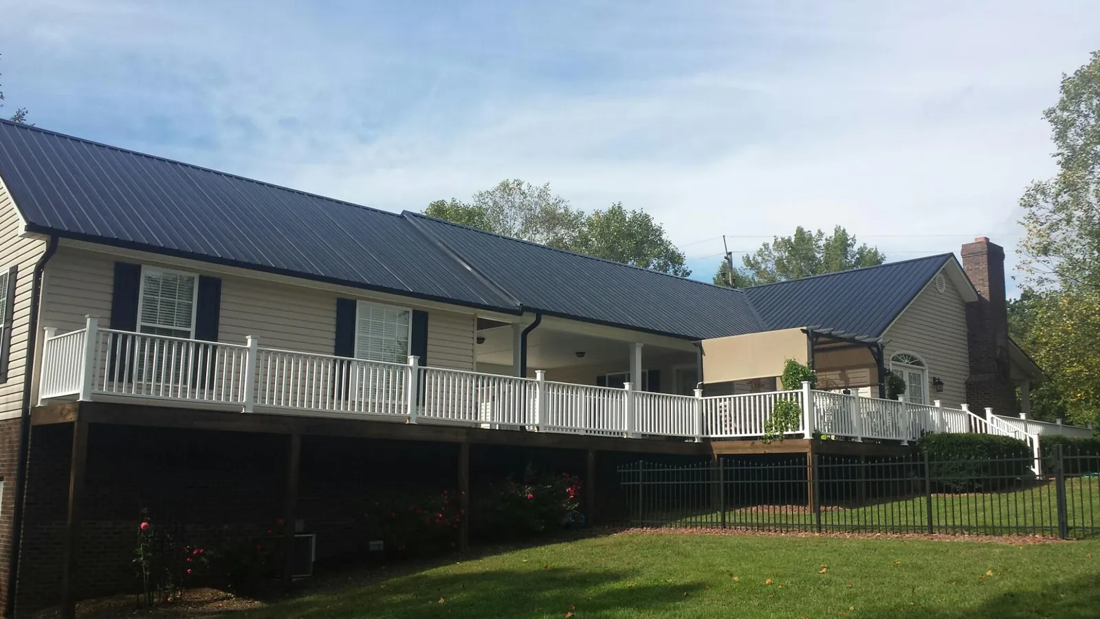 Black metal roof above a long white railed deck on a hillside home in Franklin